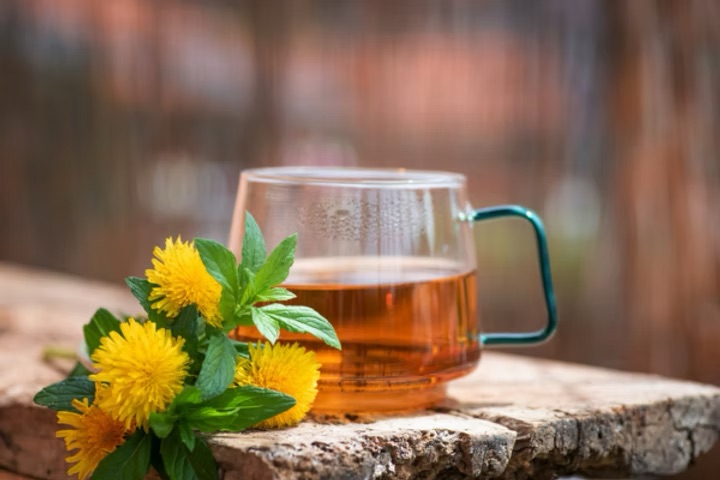 cup of tea with flowers and herb next to the cup